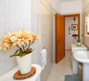 a bathroom with a vase with yellow flowers on a counter at Dimora La Cupa in Monteroni di Lecce