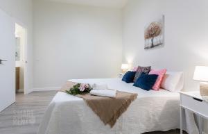 a white bedroom with a large bed with flowers on it at La Fuente de la Casona in Jerez de la Frontera