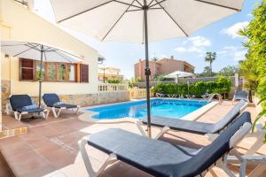 a patio with chairs and an umbrella and a pool at Villa Manrique in Cala Ratjada