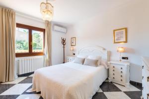 a white bedroom with a white bed and a window at Villa Manrique in Cala Ratjada +22 photos