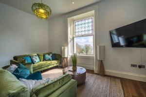 a living room with a couch and a tv at Stylish Sea View Apartment in Torquay