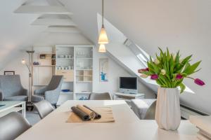 a white dining room with a vase of flowers on a table at Haus Kleemann in Norderney