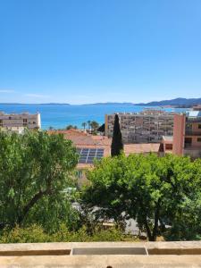 uma vista para uma cidade com árvores e o oceano em Maison centre ville vue mer em Le Lavandou