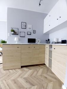 a kitchen with white walls and wooden cabinets at Studio Gruszka in Gdynia