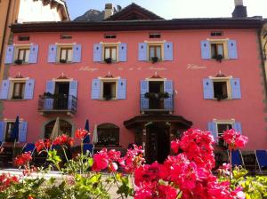 ein rosafarbenes Gebäude mit weißen Fenstern und Blumen in der Unterkunft Hotel Vittoria - Ca' De La Montagna in Montespluga