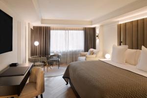 エスカルデス・エンゴルダニにあるHotel MIM Andorraのベッド、デスク、椅子が備わるホテルルームです。