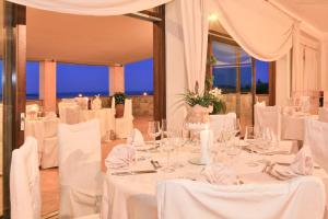 une salle à manger avec des tables et des chaises blanches dans l'établissement Hotel Micalosu, à Cannigione