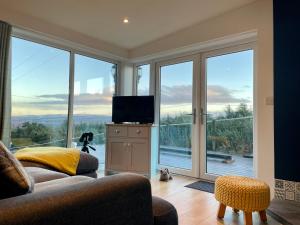 a living room with a tv and large glass windows at Woodside Cabin in Inverness