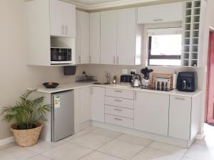 a white kitchen with white cabinets and a plant at Studio's@360onChurch in Pretoria