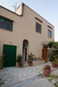 uma casa com uma porta verde e algumas plantas em Vito nel Baglio em Scopello
