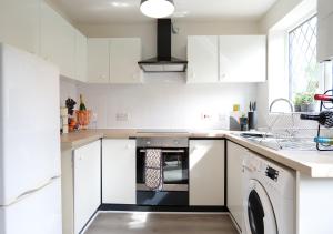 een keuken met witte kasten en een vaatwasser bij Modern Spark Home with parking, garden, Wi-Fi in Birmingham