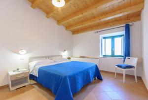 um quarto com uma cama azul e uma cadeira em Vito nel Baglio em Scopello