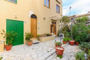 uma casa com uma porta verde e vasos de plantas em Vito nel Baglio em Scopello