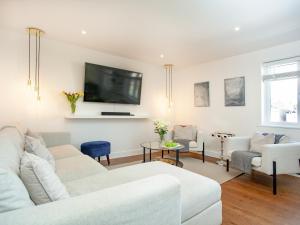 sala de estar con muebles blancos y TV de pantalla plana en Eugene Sands en Paignton