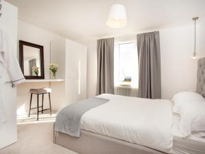 a white bedroom with a bed and a window at Eugene Sands in Paignton