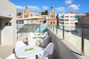 a balcony with white tables and white chairs at Hotel Macià Granada Five Senses Rooms & Suites in Granada