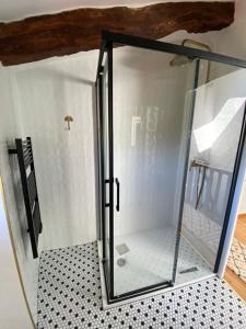 a glass shower door in a bathroom with a tiled floor at Maison Albertine in Creissels