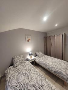 een slaapkamer met 2 bedden en een tafel met een lamp bij Appartement Le Duplex in Cluny