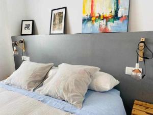 マラガにあるAcogedor Apartamento en el Centro de Málagaのベッド1台(枕2つ付)、上に絵画