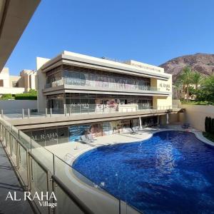 a building with a large swimming pool in front of it at Rental unit in alraha village -marsa zayed مرسى زايد- قرية الراحة in Aqaba