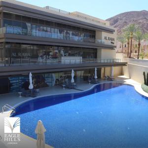 a hotel with a large swimming pool in front of a building at Rental unit in alraha village -marsa zayed مرسى زايد- قرية الراحة in Aqaba