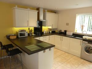 a kitchen with white cabinets and a washer and dryer at Hendre Wen holiday cottage in Betws-y-coed