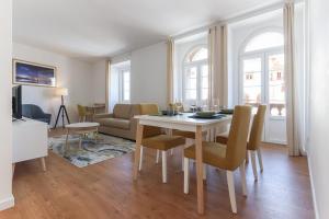 Sintra Flower Lux Apartments في سينترا: غرفة معيشة مع طاولة طعام مع كراسي