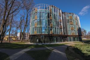 un edificio con una fachada de cristal en un parque en SOLEMI, en Druskininkai