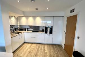 a kitchen with white cabinets and a wooden floor at Luxury Top Floor Apartment in London in London