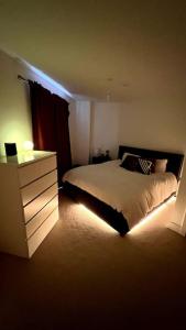 - une chambre avec un lit et une commode éclairée dans l'établissement Luxury Top Floor Apartment in London, à Londres