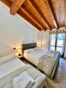 two beds in a room with wooden ceilings and windows at Residence la Lucciola in Lonato