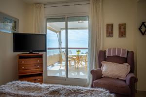 sala de estar con TV, silla y mesa en AT100 Antina Mar, en Torredembarra