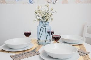 a table with three white bowls and glasses of wine at Cozy Nights Letnicka by Renters Prestige in Gdańsk