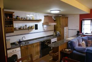 a kitchen with a blue couch and a counter top at La Casa Verde del Sella in Mesariegos +8 photos