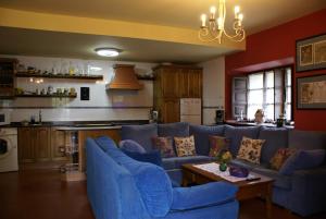 a living room with blue couches and a kitchen at La Casa Verde del Sella in Mesariegos