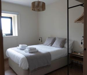 Un dormitorio con una cama blanca con toallas. en Casa Caliza, en Puertas