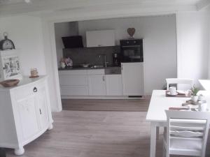 cocina con armarios blancos y mesa blanca en House Louise. en Risum-Lindholm