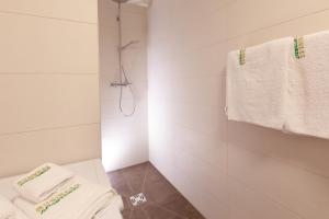 a white bathroom with white towels and a shower at Wohlfühlapartments in Hard in Hard