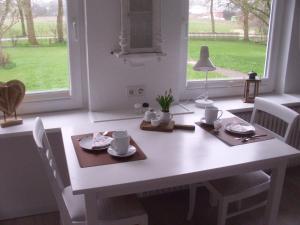 einen weißen Tisch und Stühle mit einem Tisch und einem Fenster in der Unterkunft House Louise. in Risum-Lindholm