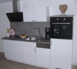 eine Küche mit einer Spüle und einer Mikrowelle in der Unterkunft House Louise. in Risum-Lindholm
