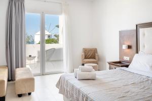 Habitación blanca con cama y balcón. en Orizontes Hotel Santorini en Pirgos