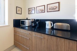 a kitchen with a black counter top with a microwave at Fábrica da Ribeira 71 by Destination Algarve in Lagos