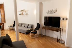 a living room with a couch and a flat screen tv at Suite Alhambra Puerta Bib-Rambla in Granada
