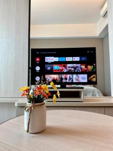 a vase of flowers sitting on a table in front of a television at TheEden#13 SwissGardenKL in Kuala Lumpur