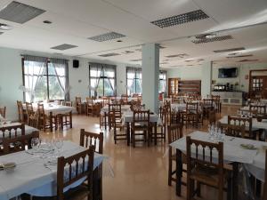 a dining room with white tables and wooden chairs at Hostal Restaurante Venta del Barro in La Puebla de Híjar