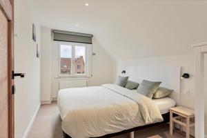 a white bedroom with a bed and a window at Maison Victor in Koksijde