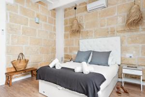 ein Schlafzimmer mit einem weißen Bett in einer Ziegelwand in der Unterkunft Hotel Boutique Ses 5 Claus in Ciutadella