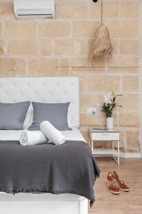 a bedroom with a white bed and a brick wall at Hotel Boutique Ses 5 Claus in Ciutadella