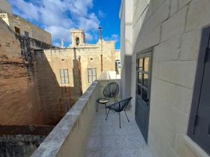 uma varanda com duas cadeiras e um edifício em House of W em Valletta