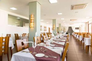 uma sala de jantar com mesas e cadeiras com toalhas de mesa brancas em Ramada by Wyndham Furnaspark em Formiga